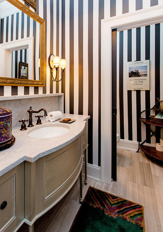 Immagine di una stanza da bagno con doccia classica di medie dimensioni con lavabo da incasso, ante in legno chiaro, top in marmo, WC monopezzo, pareti nere e pavimento in legno massello medio