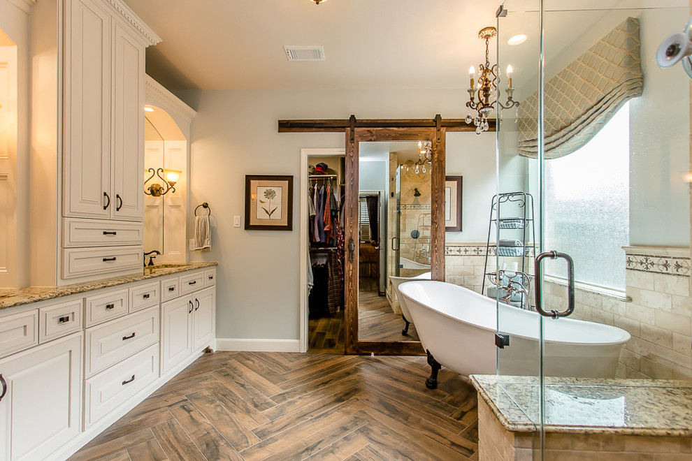 На фото: главная ванная комната в классическом стиле с фасадами с выступающей филенкой, белыми фасадами, отдельно стоящей ванной, серыми стенами и врезной раковиной