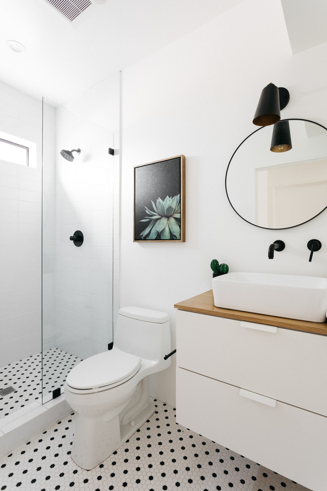 Modernes Badezimmer mit flächenbündigen Schrankfronten, weißen Schränken, weißen Fliesen, weißer Wandfarbe, Mosaik-Bodenfliesen, Aufsatzwaschbecken, Waschtisch aus Holz, buntem Boden und brauner Waschtischplatte in Los Angeles