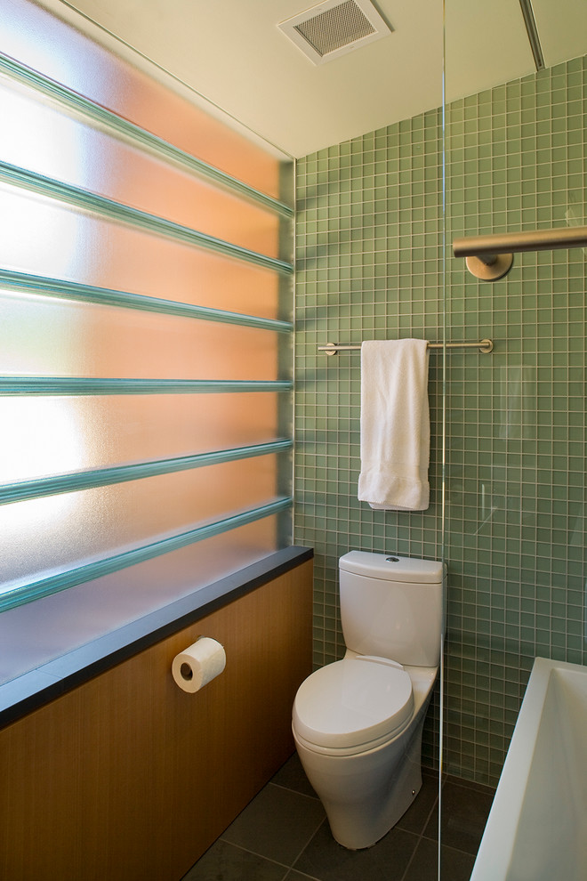 На фото: большая ванная комната в современном стиле с раздельным унитазом, зеленой плиткой, стеклянной плиткой, полом из керамической плитки и душем над ванной с