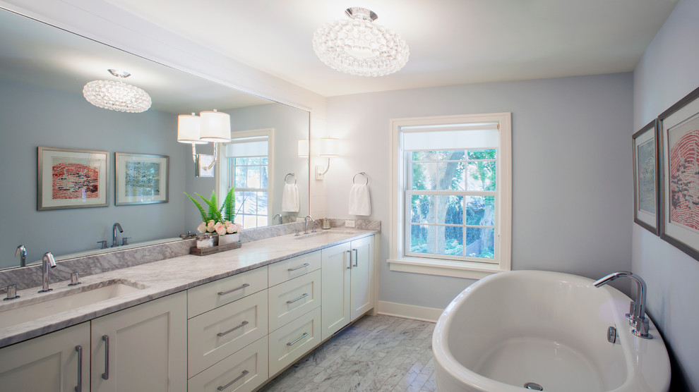 Design ideas for a medium sized classic ensuite bathroom in Grand Rapids with a submerged sink, recessed-panel cabinets, white cabinets, marble worktops, a freestanding bath, grey tiles, blue walls and marble flooring.
