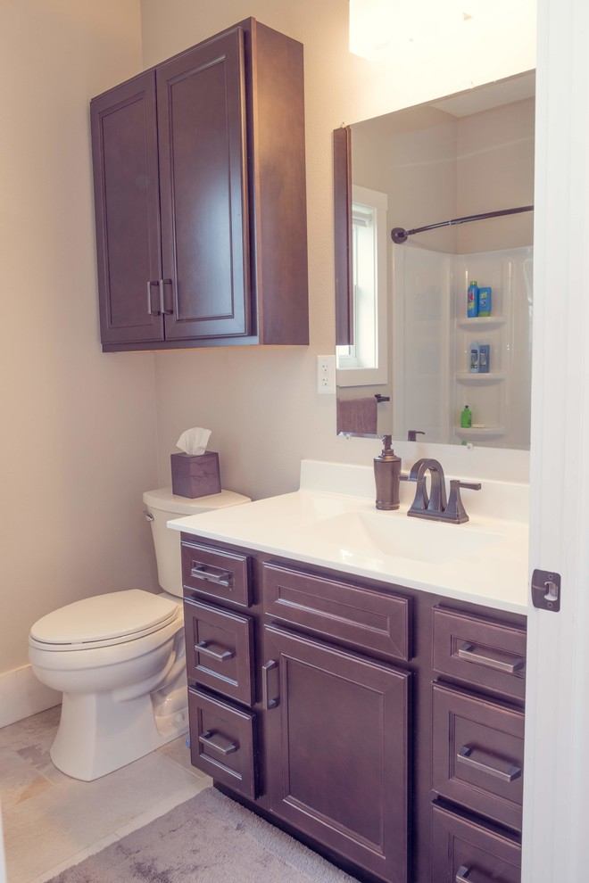 Classic family bathroom in Cedar Rapids with recessed-panel cabinets, dark wood cabinets, an alcove bath, a shower/bath combination, a two-piece toilet, beige walls, porcelain flooring, an integrated sink, solid surface worktops, white floors, a shower curtain and white worktops.