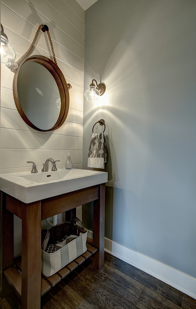 Inredning av ett amerikanskt litet badrum med dusch, med öppna hyllor, skåp i mellenmörkt trä, blå väggar, mellanmörkt trägolv, ett integrerad handfat, bänkskiva i akrylsten och brunt golv