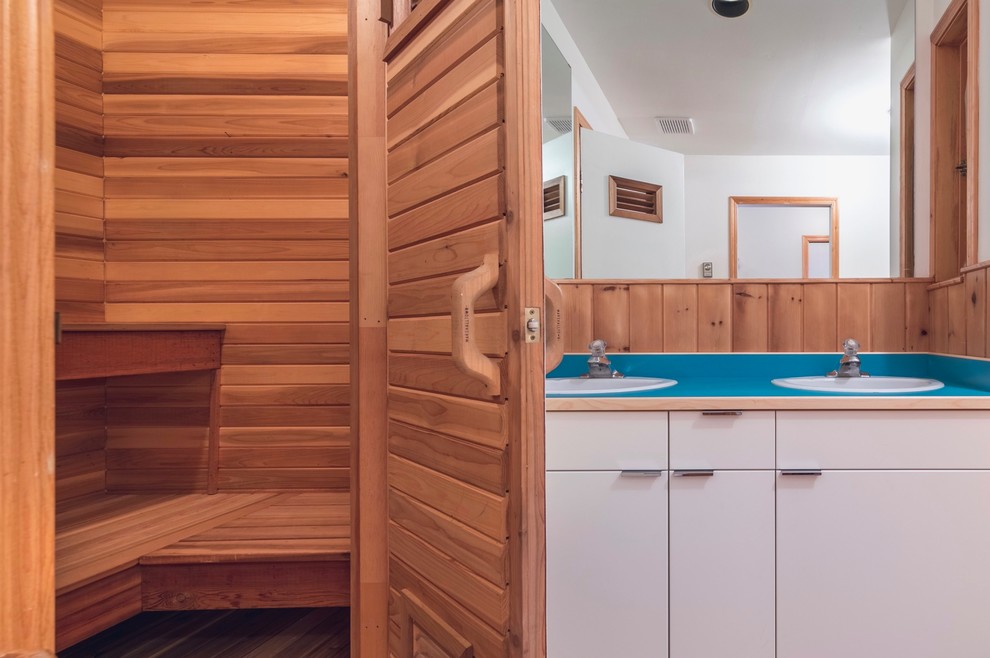 Exemple d'un sauna montagne de taille moyenne avec un placard à porte plane, des portes de placard blanches, une baignoire en alcôve, un combiné douche/baignoire, un mur marron, un sol en bois brun, un plan vasque, un plan de toilette en stratifié, un sol marron, aucune cabine et un plan de toilette bleu.