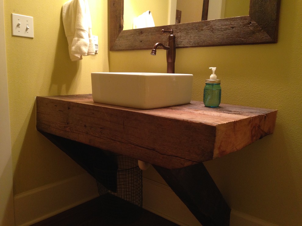 Immagine di una piccola stanza da bagno con doccia rustica con lavabo a bacinella, top in legno, pareti gialle e pavimento in legno massello medio