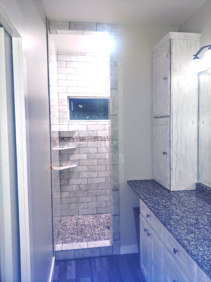 На фото: большая главная ванная комната в стиле неоклассика (современная классика) с фасадами в стиле шейкер, белыми фасадами, душем в нише, разноцветной плиткой, мраморной плиткой, серыми стенами, полом из ламината, столешницей из гранита, разноцветным полом, тумбой под одну раковину и встроенной тумбой с