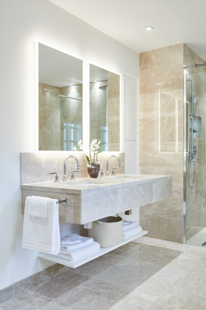 Inspiration for a large contemporary ensuite bathroom in Cardiff with beige cabinets, beige tiles, white walls, a submerged sink, grey floors, beige worktops, double sinks, a floating vanity unit, a walk-in shower, a wall mounted toilet, marble flooring, marble worktops and an open shower.