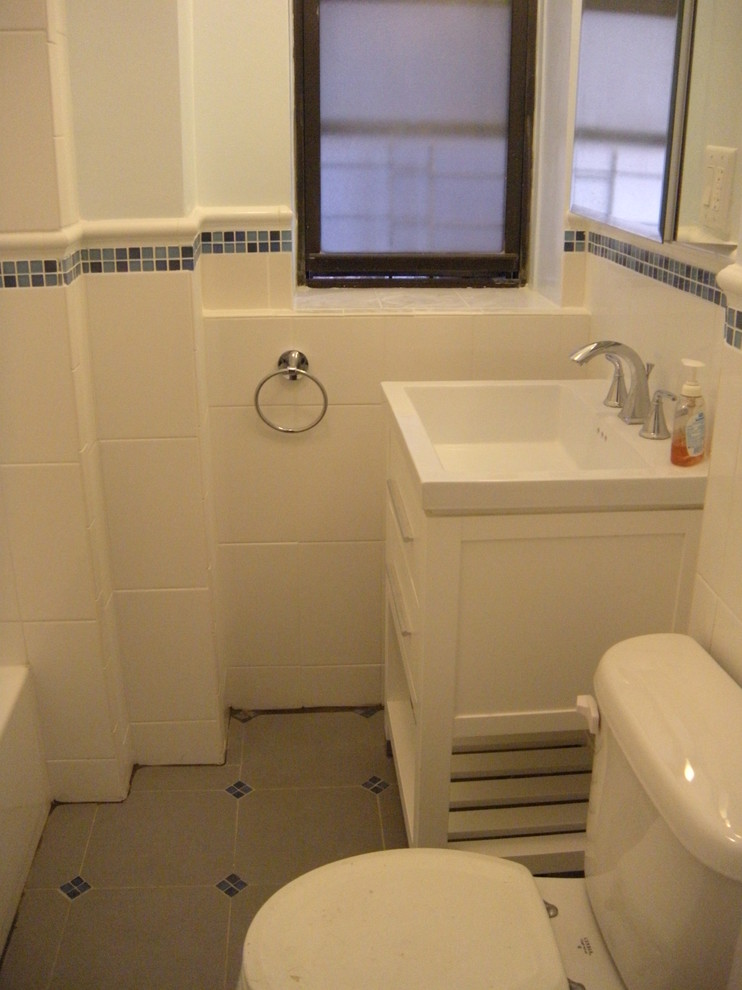 На фото: ванная комната в классическом стиле с монолитной раковиной, плоскими фасадами, белыми фасадами, душем над ванной, раздельным унитазом, белой плиткой, керамогранитной плиткой, белыми стенами и полом из керамической плитки