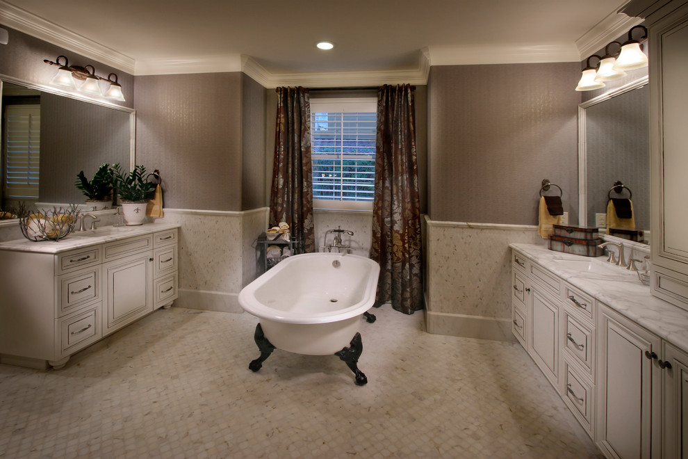 Inspiration for a large timeless master porcelain tile and gray floor claw-foot bathtub remodel in Denver with raised-panel cabinets, beige cabinets, brown walls, an undermount sink, marble countertops and gray countertops