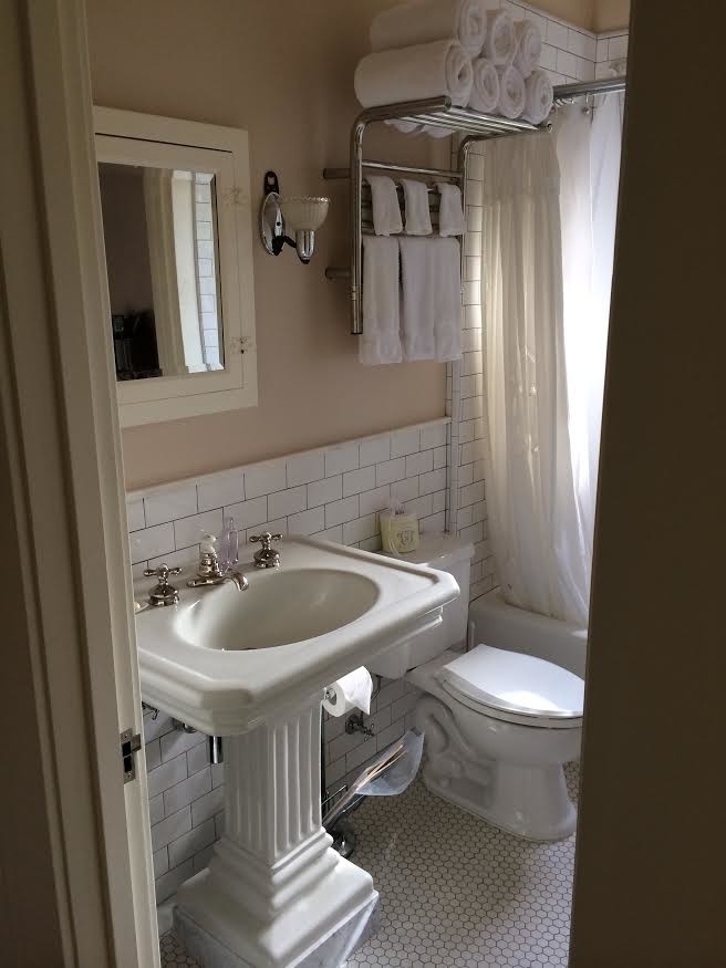 Пример оригинального дизайна: маленькая ванная комната в классическом стиле с стеклянными фасадами, белыми фасадами, ванной в нише, душем над ванной, раздельным унитазом, белой плиткой, плиткой кабанчик, бежевыми стенами, полом из керамической плитки, душевой кабиной, раковиной с пьедесталом, белым полом и шторкой для ванной для на участке и в саду