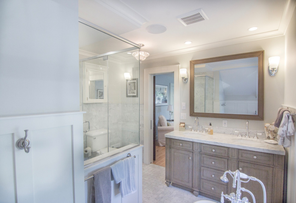 Large elegant master multicolored tile and marble tile marble floor, gray floor, double-sink and wainscoting bathroom photo in Other with raised-panel cabinets, brown cabinets, a two-piece toilet, gray walls, an undermount sink, a hinged shower door, gray countertops and a freestanding vanity