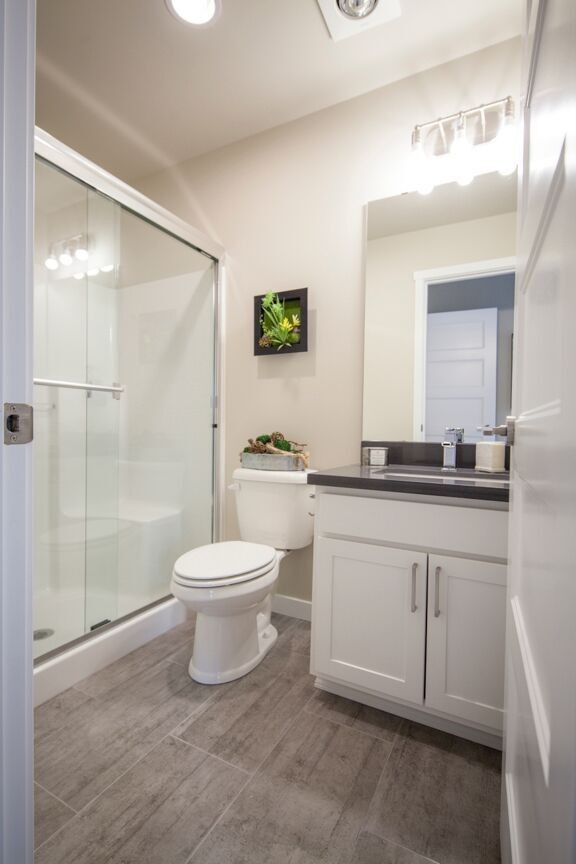 Foto de cuarto de baño clásico renovado con armarios con paneles con relieve, puertas de armario blancas, ducha doble, sanitario de una pieza, paredes beige y suelo de madera en tonos medios