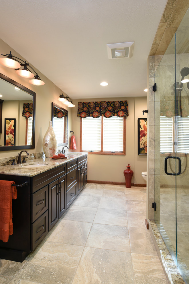 Large traditional ensuite bathroom in Other with a submerged sink, raised-panel cabinets, dark wood cabinets, granite worktops, an alcove shower, a two-piece toilet, beige tiles, porcelain tiles, beige walls, porcelain flooring and beige floors.
