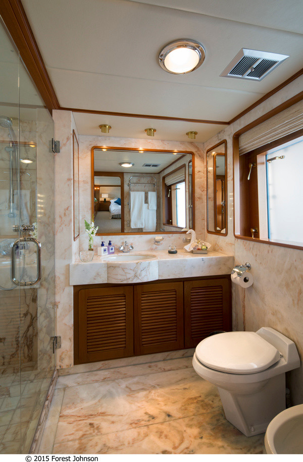 Ispirazione per una stanza da bagno padronale minimal di medie dimensioni con ante in legno scuro, ante a persiana, doccia alcova, WC monopezzo, pareti beige, pavimento in marmo, lavabo integrato e top in marmo