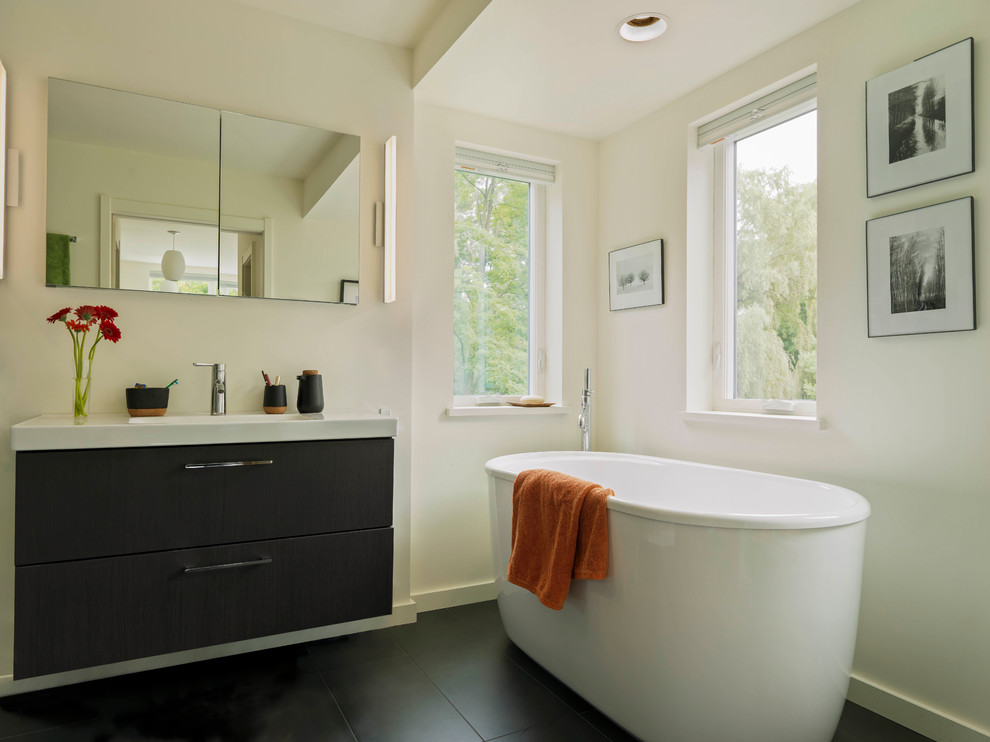 На фото: главная ванная комната в стиле модернизм с плоскими фасадами, черными фасадами, отдельно стоящей ванной, полом из керамогранита, черным полом, белой столешницей, тумбой под одну раковину и подвесной тумбой с