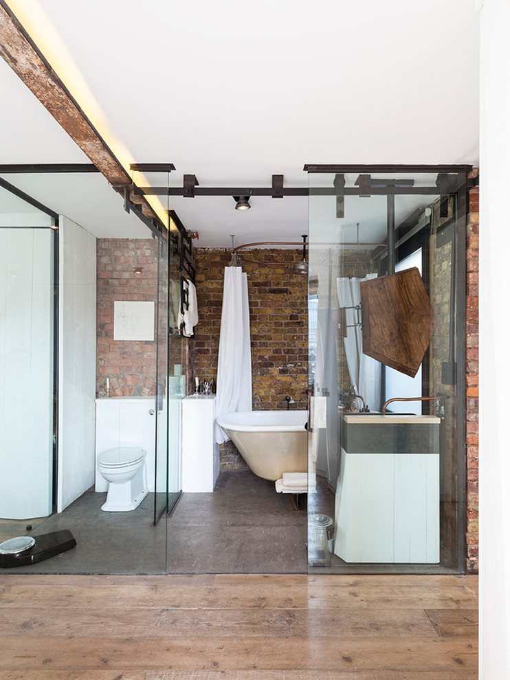 ロンドンにあるラグジュアリーな小さなインダストリアルスタイルのおしゃれな浴室 (白いキャビネット、置き型浴槽、一体型トイレ	、シャワーカーテン) の写真
