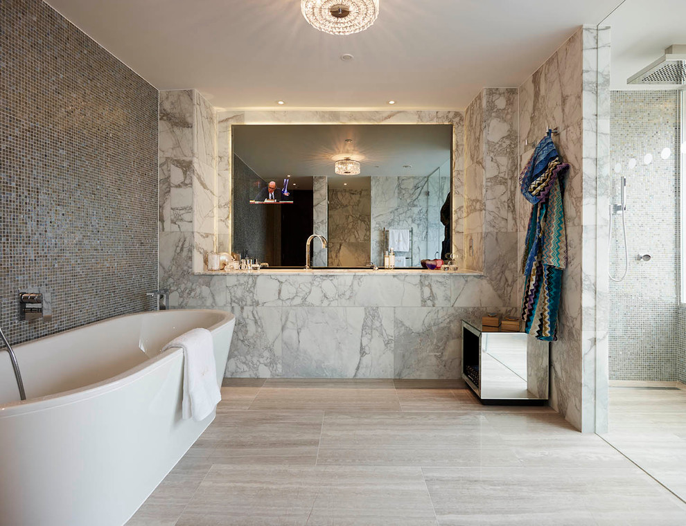 Example of a trendy gray tile freestanding bathtub design in London