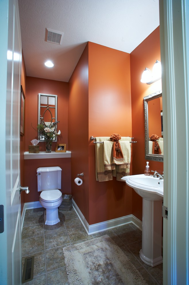 Bathroom - mid-sized traditional 3/4 ceramic tile bathroom idea in Columbus with a two-piece toilet, orange walls, a pedestal sink and solid surface countertops