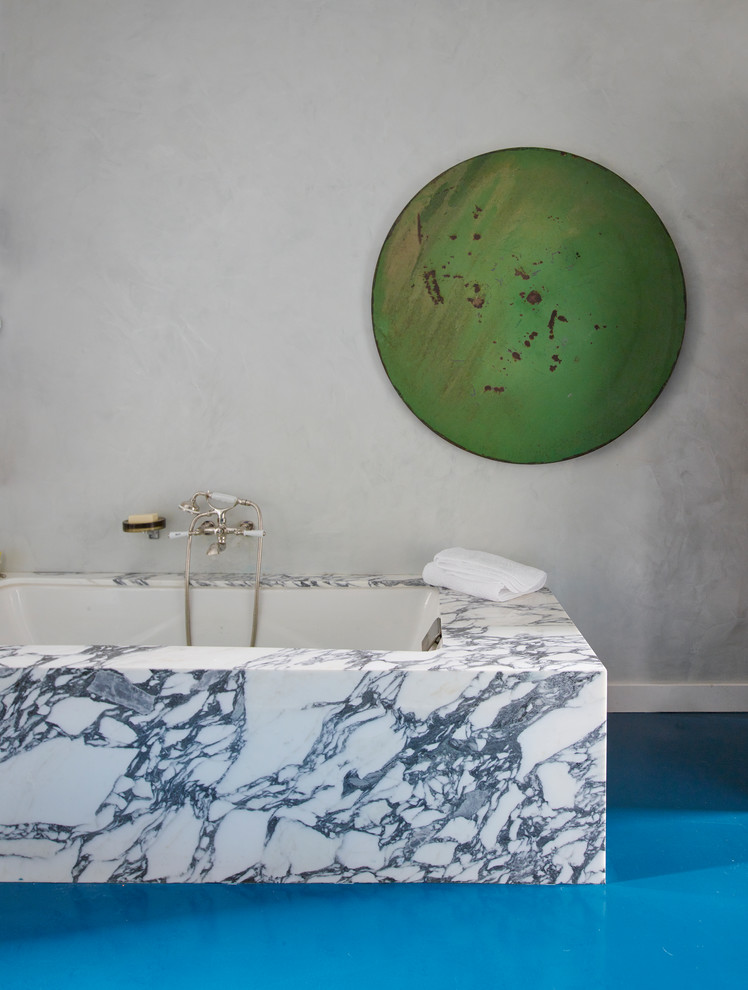 Example of a small eclectic master white tile concrete floor and blue floor freestanding bathtub design in New York with flat-panel cabinets, brown cabinets, white walls, a wall-mount sink, marble countertops and a hinged shower door