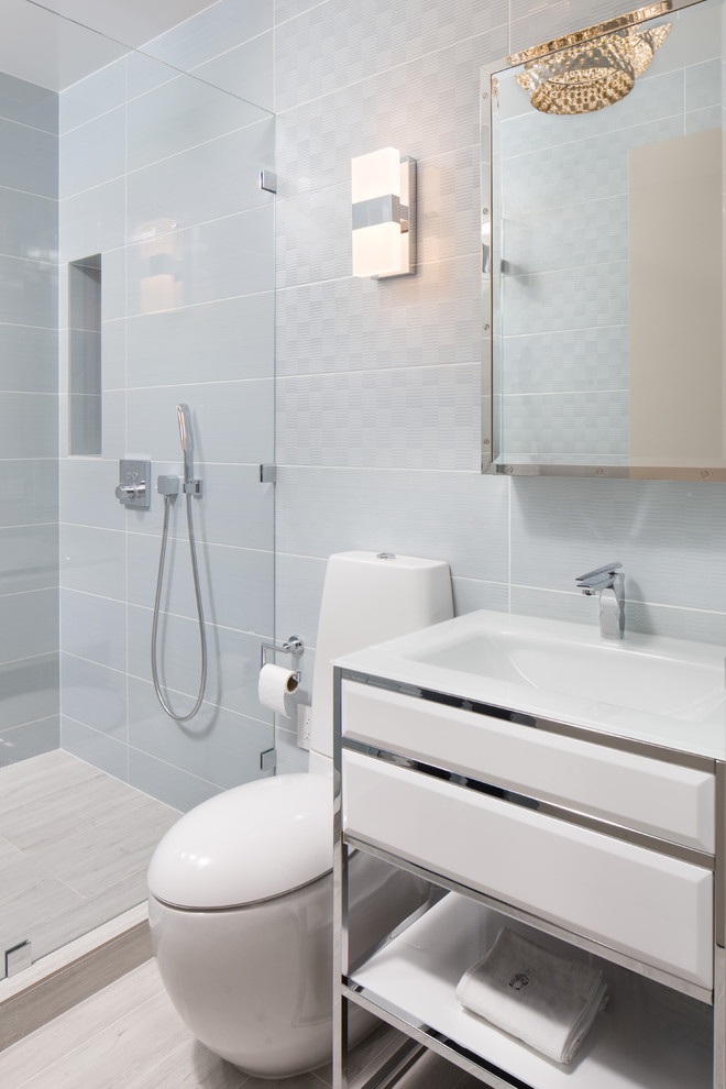 Example of a mid-sized minimalist kids' blue tile and ceramic tile ceramic tile and beige floor alcove shower design in New York with raised-panel cabinets, white cabinets, a one-piece toilet, white walls, an integrated sink, quartz countertops, a hinged shower door and white countertops