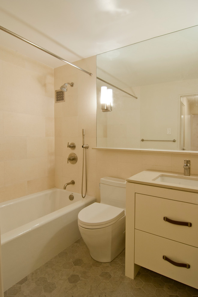 На фото: маленькая главная ванная комната в современном стиле с плоскими фасадами, бежевыми фасадами, ванной в нише, душем над ванной, унитазом-моноблоком, бежевой плиткой, плиткой из известняка, бежевыми стенами, полом из известняка, врезной раковиной, столешницей из искусственного кварца, серым полом и шторкой для ванной для на участке и в саду с