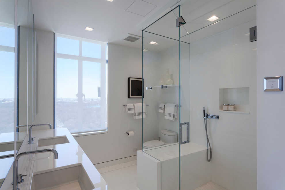 Exemple d'une grande salle de bain principale tendance avec un placard à porte plane, des portes de placard blanches, une douche ouverte, un carrelage blanc, des plaques de verre, un lavabo encastré, un plan de toilette en verre, WC à poser et un mur blanc.