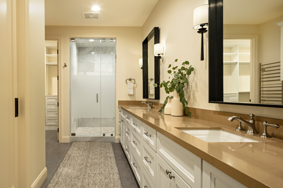 Inspiration for a medium sized traditional family bathroom in Phoenix with shaker cabinets, brown cabinets, a freestanding bath, a walk-in shower, a one-piece toilet, beige tiles, marble tiles, beige walls, light hardwood flooring, a submerged sink, engineered stone worktops, beige floors, a hinged door and black worktops.