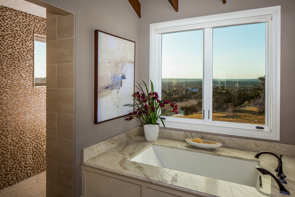 オースティンにあるトラディショナルスタイルのおしゃれなマスターバスルーム (アンダーマウント型浴槽、茶色いタイル、茶色い壁、磁器タイルの床、珪岩の洗面台) の写真