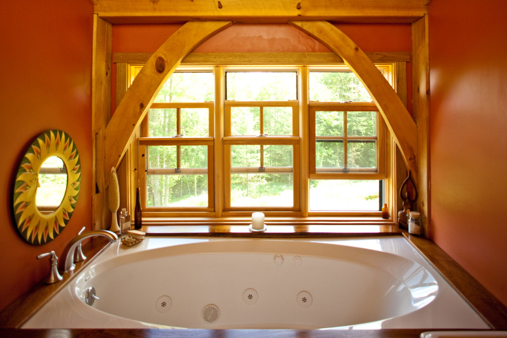 Cette image montre une petite salle de bain chalet avec un bain bouillonnant et un mur rouge.