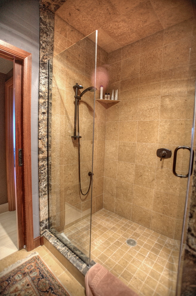 Cette image montre une grande salle de bain principale traditionnelle avec un plan de toilette en granite, une douche d'angle, un carrelage marron, un carrelage de pierre, un mur gris et un sol en travertin.
