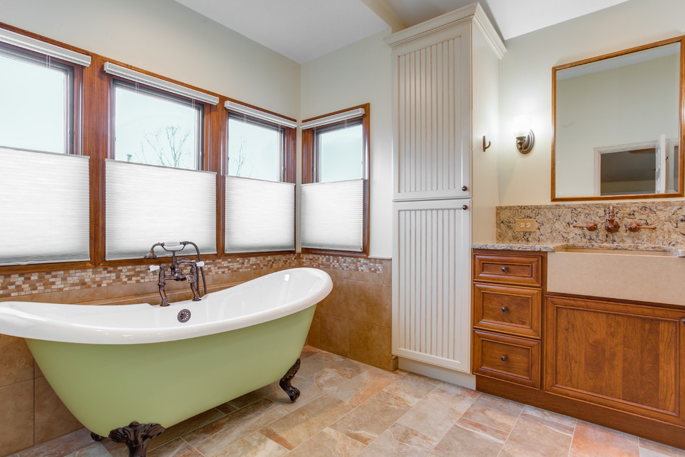 Cette image montre une grande salle de bain principale méditerranéenne avec un placard à porte affleurante, des portes de placard marrons, une baignoire sur pieds, une douche à l'italienne, WC à poser, un carrelage beige, des dalles de pierre, un mur beige, un sol en carrelage de céramique, un lavabo encastré, un plan de toilette en quartz modifié, un sol multicolore et une cabine de douche à porte battante.