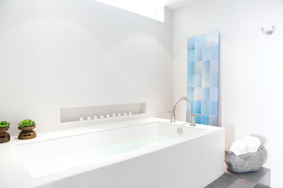 Inredning av ett modernt badrum, med ett badkar i en alkov, grå kakel och vita väggar