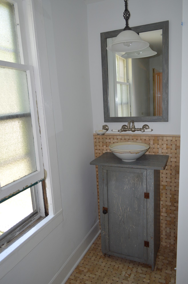 Lantlig inredning av ett litet grå grått badrum för barn, med möbel-liknande, grå skåp, brun kakel, porslinskakel, grå väggar, klinkergolv i porslin, träbänkskiva och brunt golv