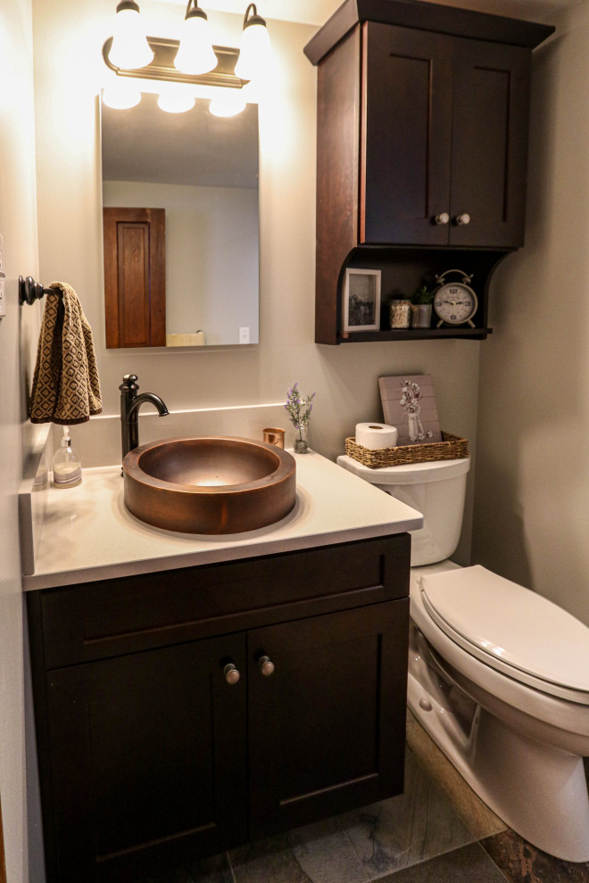 This is an example of a small country ensuite bathroom in Cleveland with recessed-panel cabinets, brown cabinets, a corner shower, a two-piece toilet, beige tiles, porcelain flooring, a vessel sink, engineered stone worktops, multi-coloured floors, a hinged door, beige worktops, a wall niche, a single sink and a freestanding vanity unit.