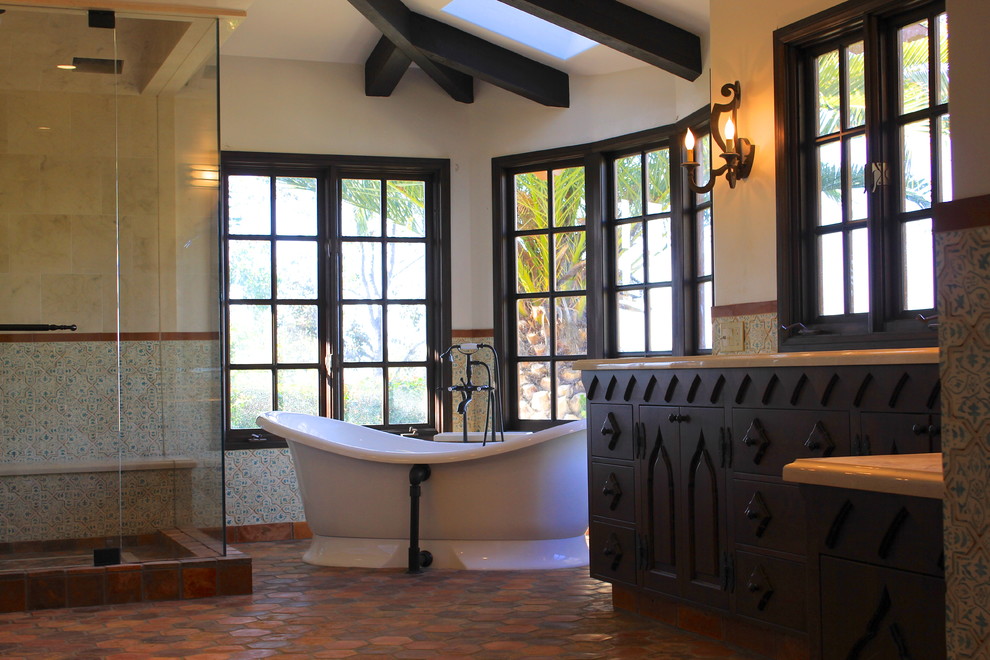 Expansive mediterranean ensuite bathroom in San Diego with a submerged sink, recessed-panel cabinets, dark wood cabinets, marble worktops, a freestanding bath, a two-piece toilet, multi-coloured tiles, terracotta tiles and white walls.