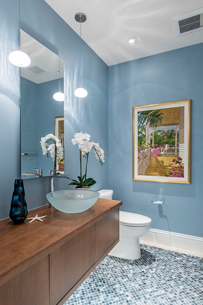Свежая идея для дизайна: ванная комната в морском стиле с плоскими фасадами, фасадами цвета дерева среднего тона, раздельным унитазом, синими стенами, полом из мозаичной плитки, настольной раковиной, столешницей из дерева, синим полом и коричневой столешницей - отличное фото интерьера