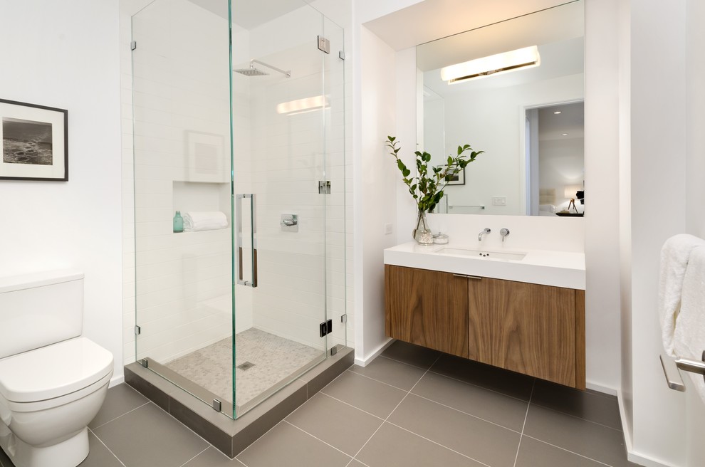 Photo of a medium sized contemporary shower room bathroom in San Francisco with flat-panel cabinets, medium wood cabinets, a corner shower, a one-piece toilet, grey tiles, porcelain tiles, white walls, porcelain flooring, a submerged sink and engineered stone worktops.