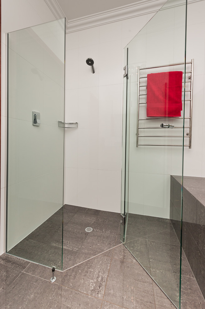 Cette image montre une douche en alcôve principale minimaliste de taille moyenne avec des portes de placard blanches, une baignoire posée, un carrelage blanc et un mur blanc.