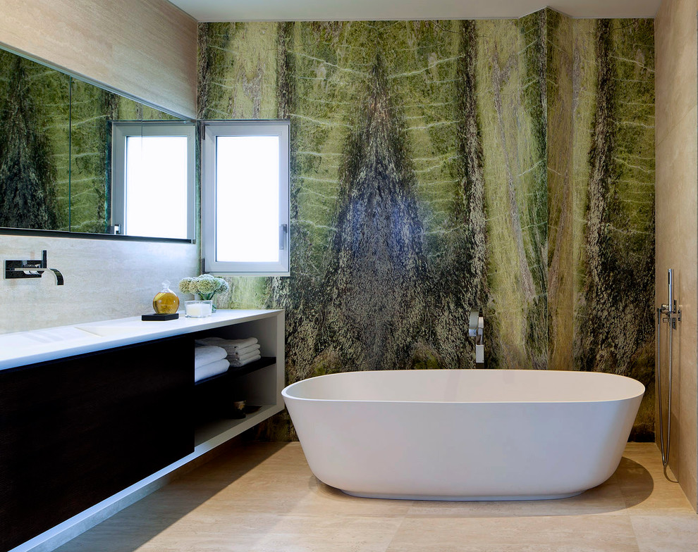 Cette image montre une salle de bain design avec une baignoire indépendante, un mur vert, du carrelage en marbre et un mur en pierre.