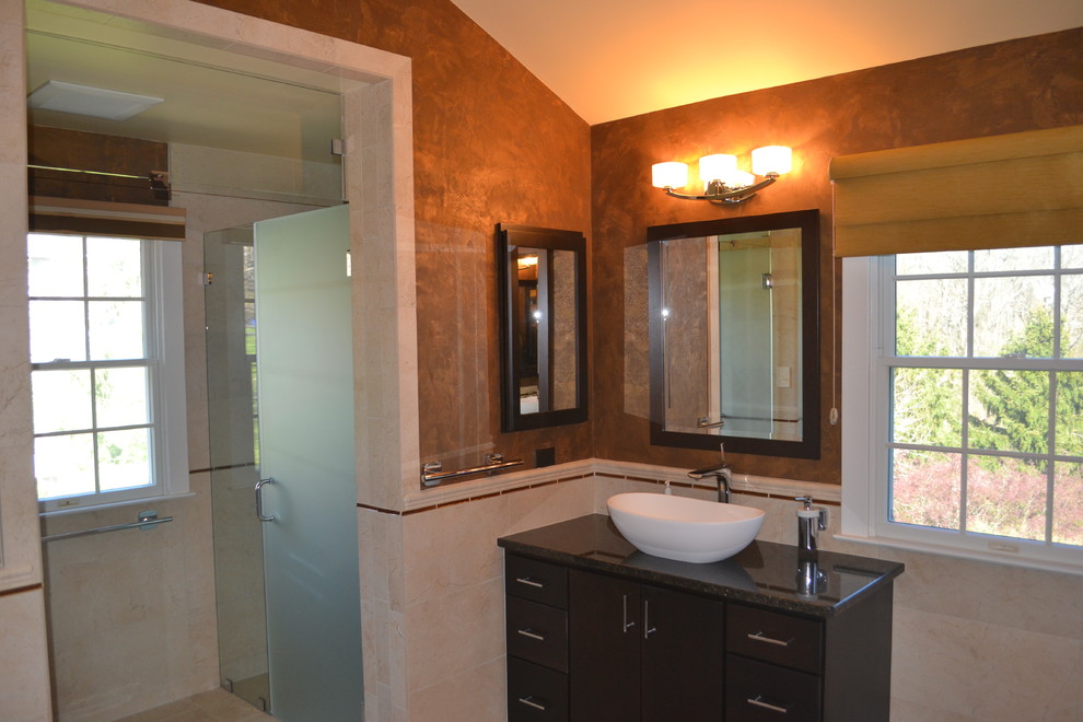 Inspiration for a large classic ensuite bathroom in Philadelphia with a vessel sink, flat-panel cabinets, medium wood cabinets, granite worktops, a corner shower, a one-piece toilet, beige tiles, ceramic tiles, brown walls and ceramic flooring.