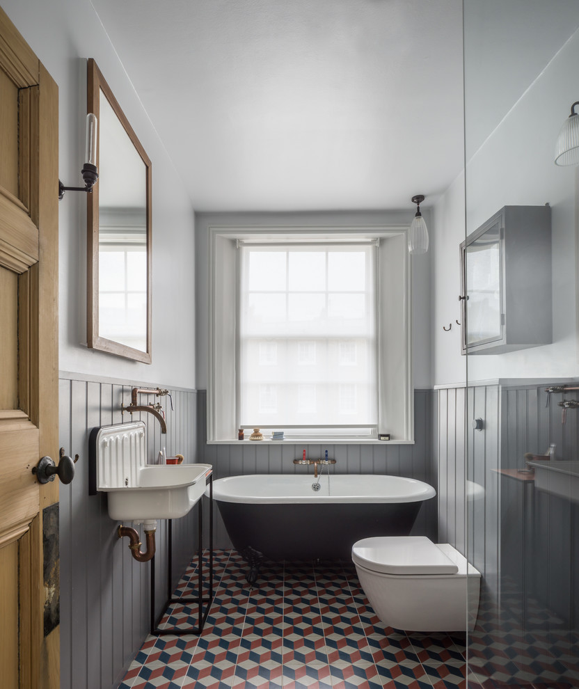 Идея дизайна: ванная комната в стиле неоклассика (современная классика) с ванной на ножках, открытым душем, инсталляцией, серыми стенами, полом из керамической плитки и подвесной раковиной