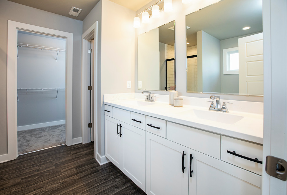 Inspiration for a medium sized traditional ensuite bathroom in Louisville with recessed-panel cabinets, white cabinets, an alcove shower, a one-piece toilet, white tiles, metro tiles, grey walls, medium hardwood flooring, an integrated sink, marble worktops, brown floors, a sliding door, white worktops, double sinks and a built in vanity unit.