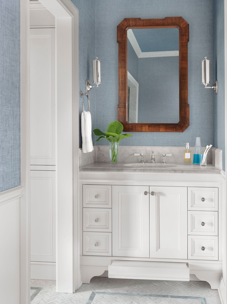 Foto på ett mellanstort vintage vit badrum, med vita skåp, blå väggar, mosaikgolv, ett undermonterad handfat, marmorbänkskiva, vitt golv och luckor med infälld panel