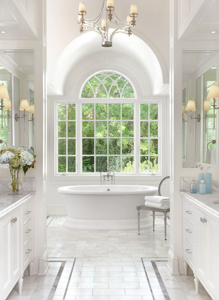 Foto på ett stort vintage vit en-suite badrum, med vita skåp, ett fristående badkar, vita väggar, marmorgolv, ett undermonterad handfat, marmorbänkskiva, vitt golv och luckor med infälld panel