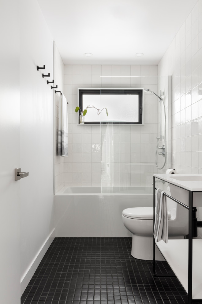 Идея дизайна: детская ванная комната в современном стиле с белыми фасадами, ванной в нише, унитазом-моноблоком, белой плиткой, керамической плиткой, белыми стенами, полом из керамической плитки, монолитной раковиной, черным полом, тумбой под одну раковину и напольной тумбой