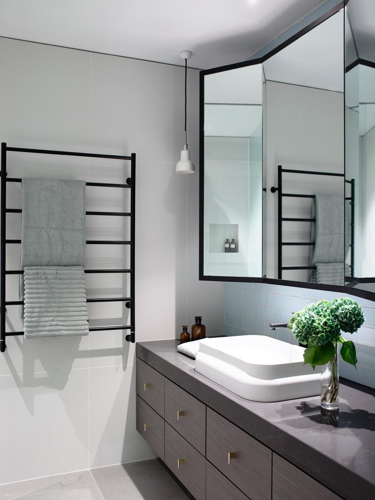 Inspiration pour une salle de bain design en bois foncé avec une vasque, un placard à porte plane et un carrelage gris.