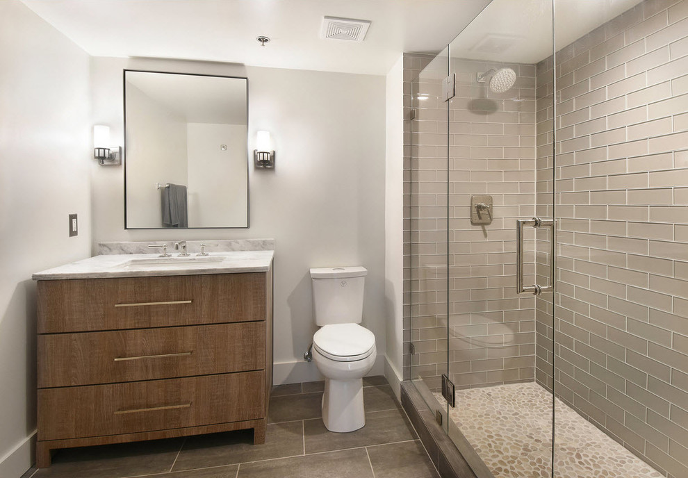 Idéer för små industriella en-suite badrum, med släta luckor, grå skåp, grå kakel, glaskakel, vita väggar, klinkergolv i porslin, marmorbänkskiva och grått golv