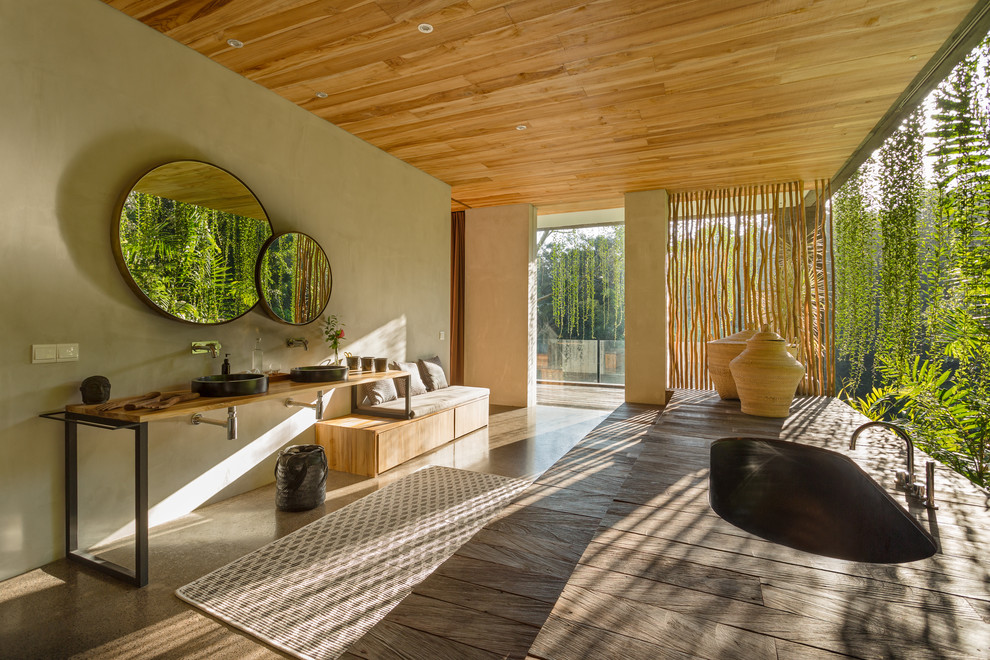 Foto på ett tropiskt en-suite badrum, med släta luckor, skåp i mellenmörkt trä, ett undermonterat badkar, grå väggar, ett fristående handfat, träbänkskiva och brunt golv