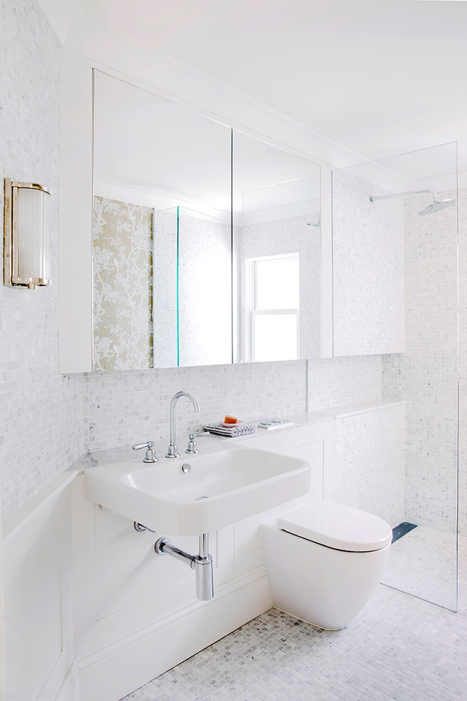 Bild på ett funkis badrum med dusch, med en kantlös dusch, en vägghängd toalettstol, grå kakel, vit kakel, mosaik, vita väggar, mosaikgolv, ett väggmonterat handfat, vitt golv och med dusch som är öppen