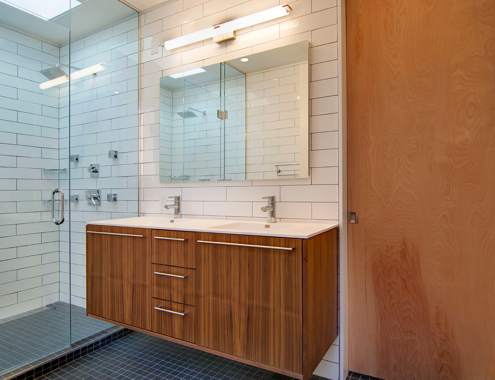 Идея дизайна: главная ванная комната среднего размера в современном стиле с монолитной раковиной, плоскими фасадами, темными деревянными фасадами, столешницей из искусственного кварца, двойным душем, белой плиткой, плиткой кабанчик и полом из мозаичной плитки